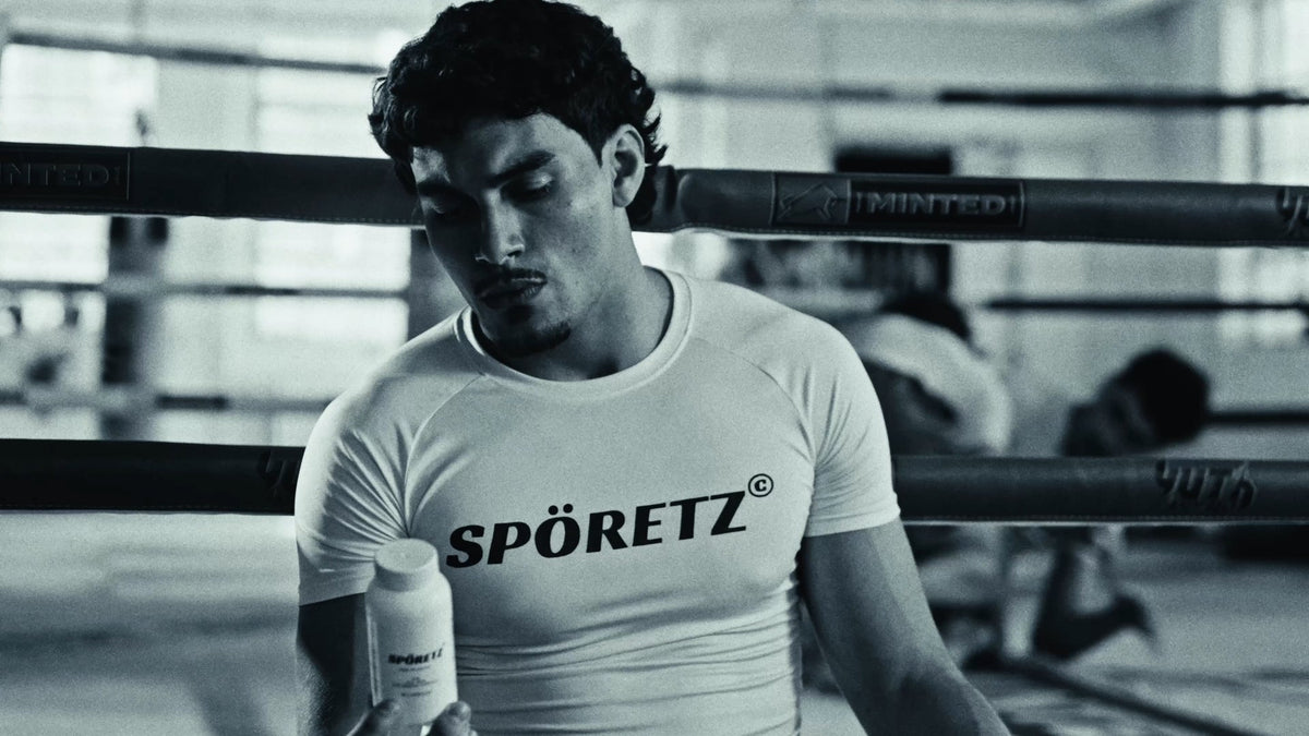 Fighter in a white Spöretz rashguard holding the MB40 bottle in a boxing ring, black-and-white