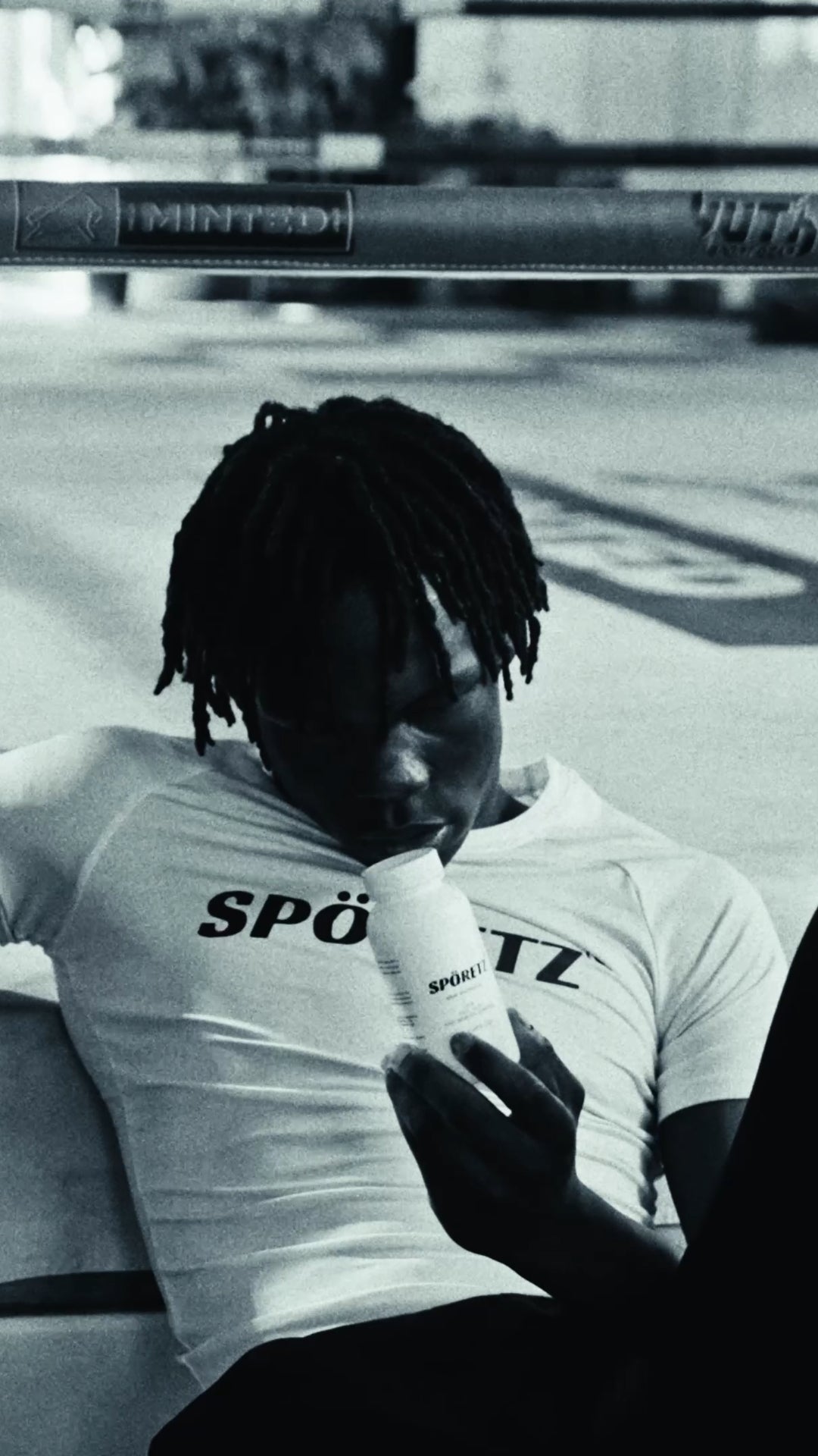 Black-and-white photo of an athlete in a white Spöretz tee drinking from the MB40 bottle